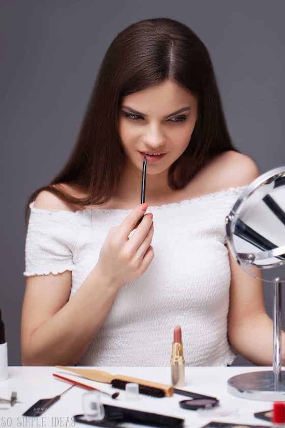 applying lipstick at desk