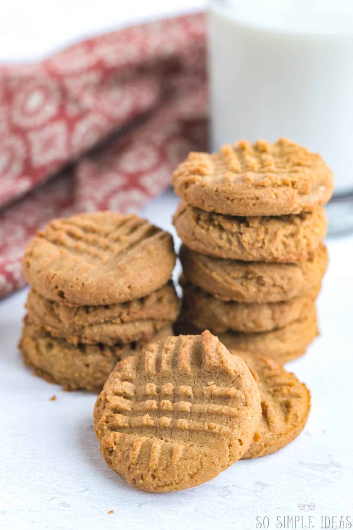 keto 3 ingredient peanut butter cookies in stacks with milk