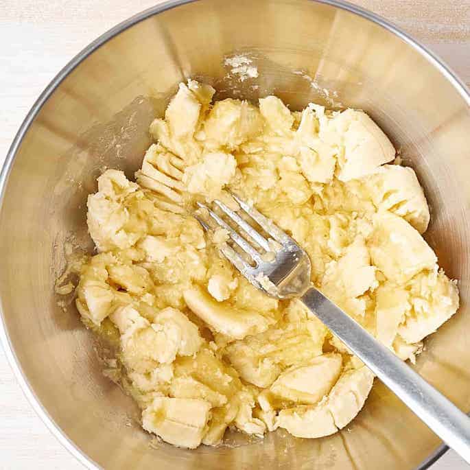 mashing sliced bananas in bowl