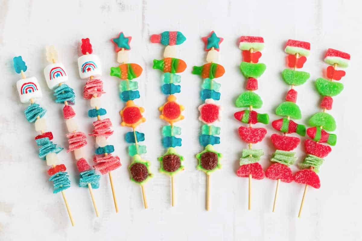 various themed gummy candy kebobs on white background