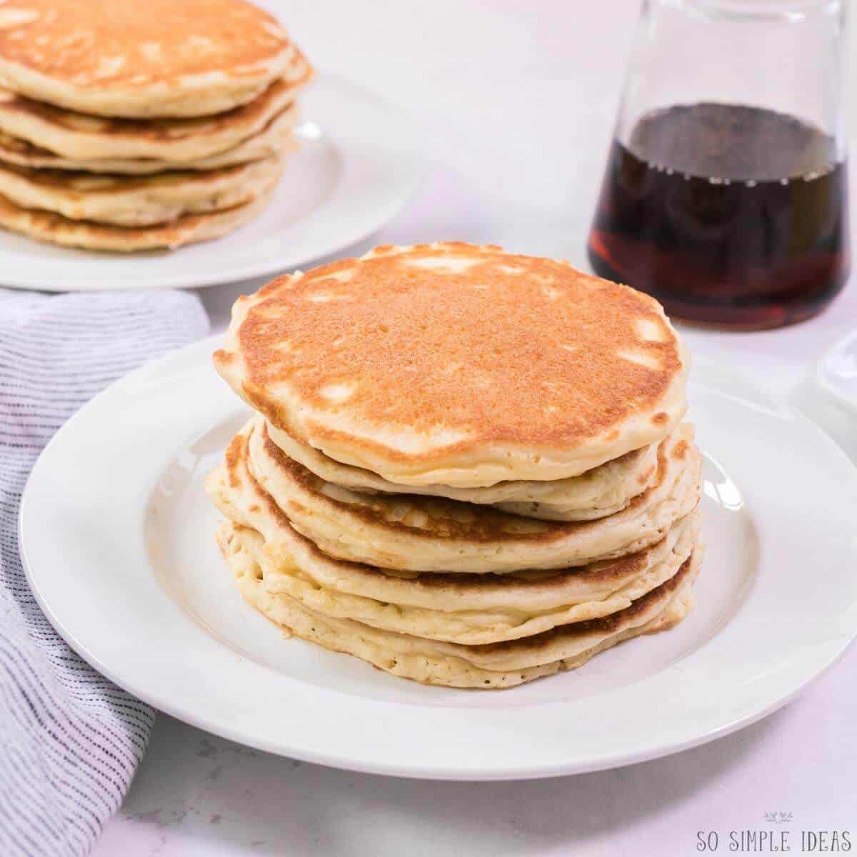 stacks of carbquik pancakes on white plates with syrup container