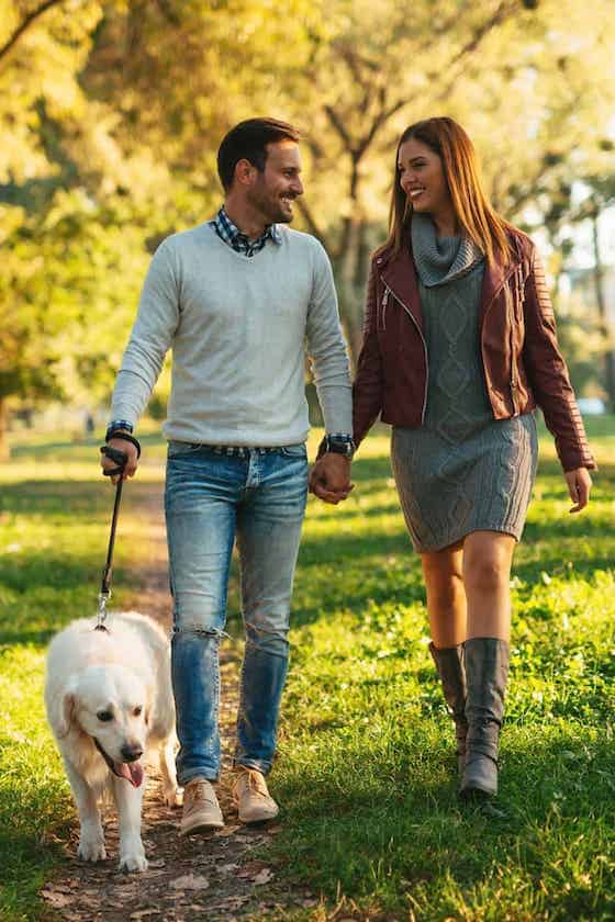 couple walking together in park with dog.