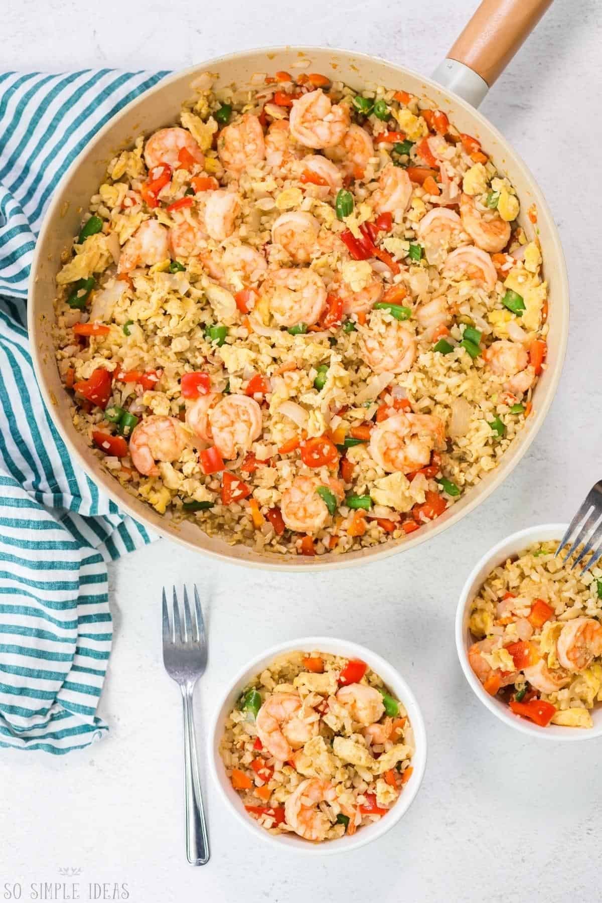 keto shrimp fried rice in skilled and two small bowls.