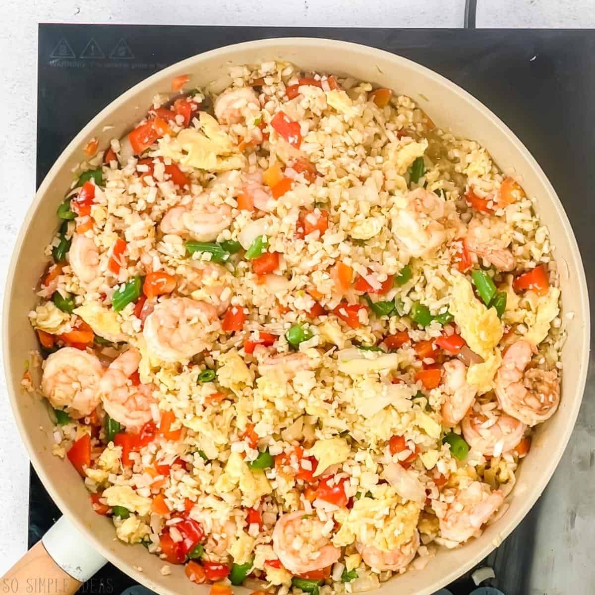 keto shrimp cauliflower rice in skillet on cooktop.