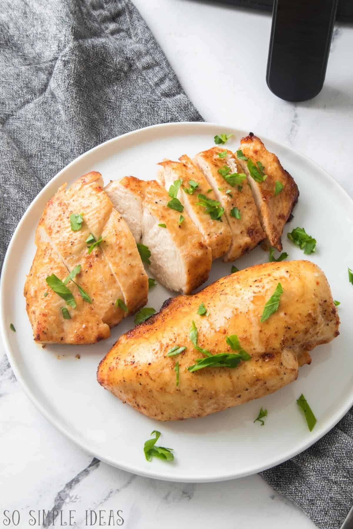 air fryer marinated chicken breasts on white plate.