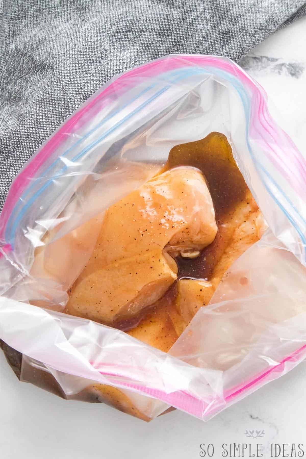 pouring marinade over uncooked chicken breasts in zipper bag.