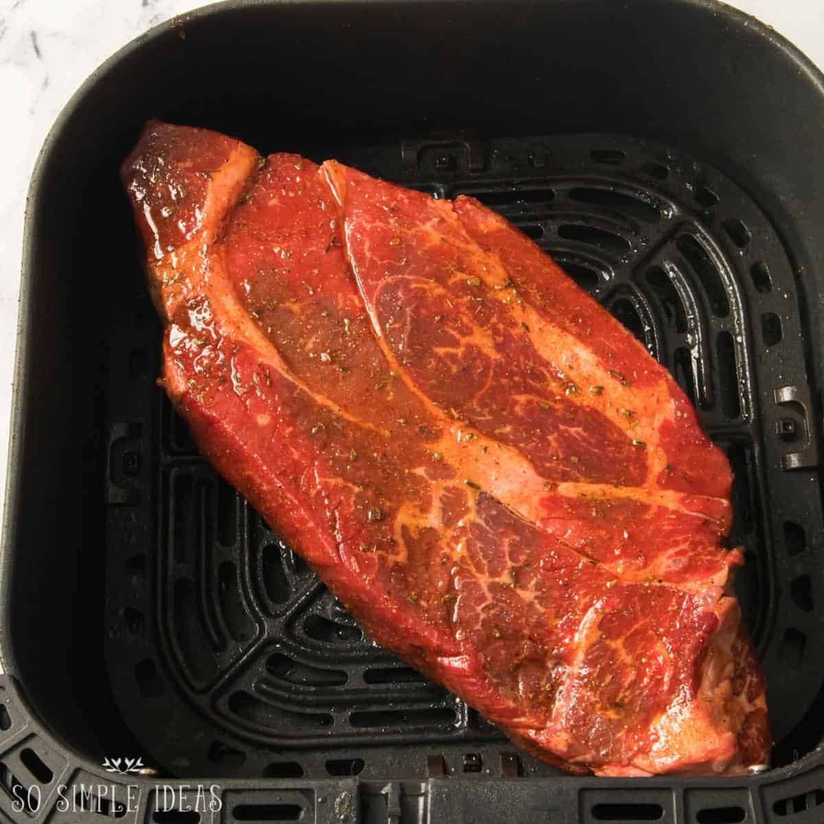 uncooked roast beef in air fryer basket.