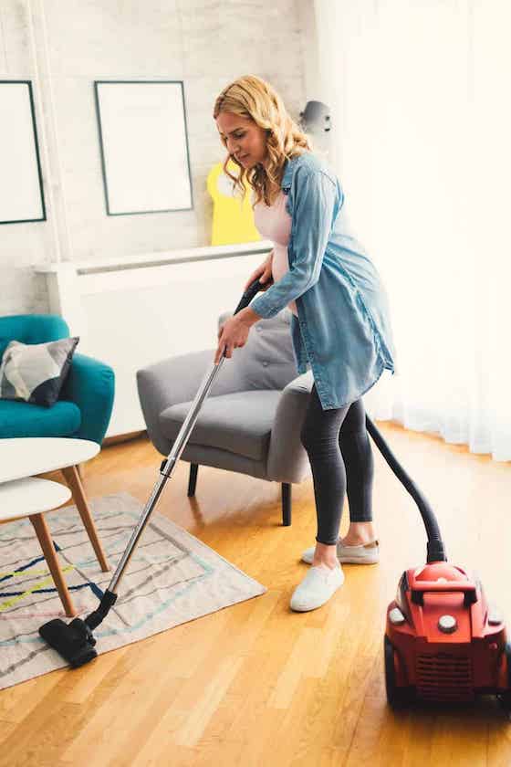 woman vacuuming an area rug.
