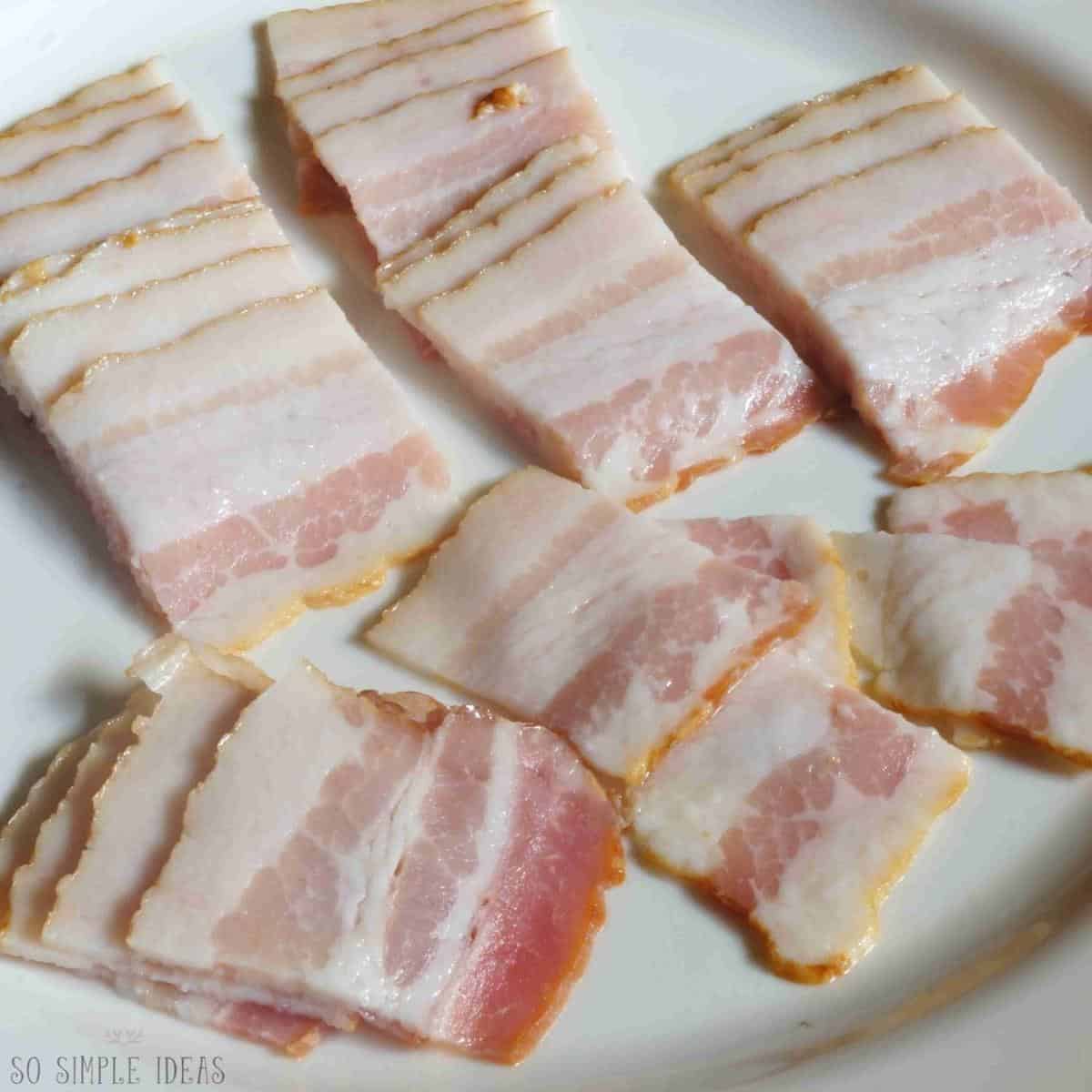 raw cut bacon on white plate.
