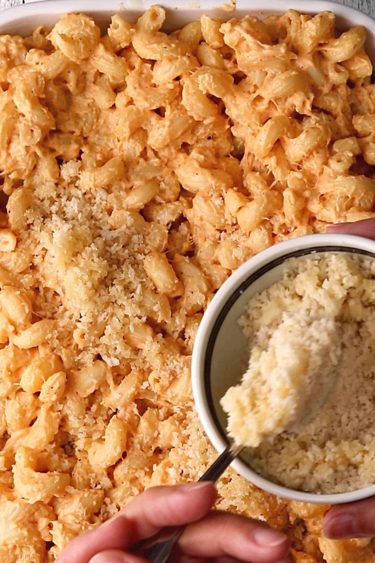 adding breadcrumbs to top of macaroni mixture.