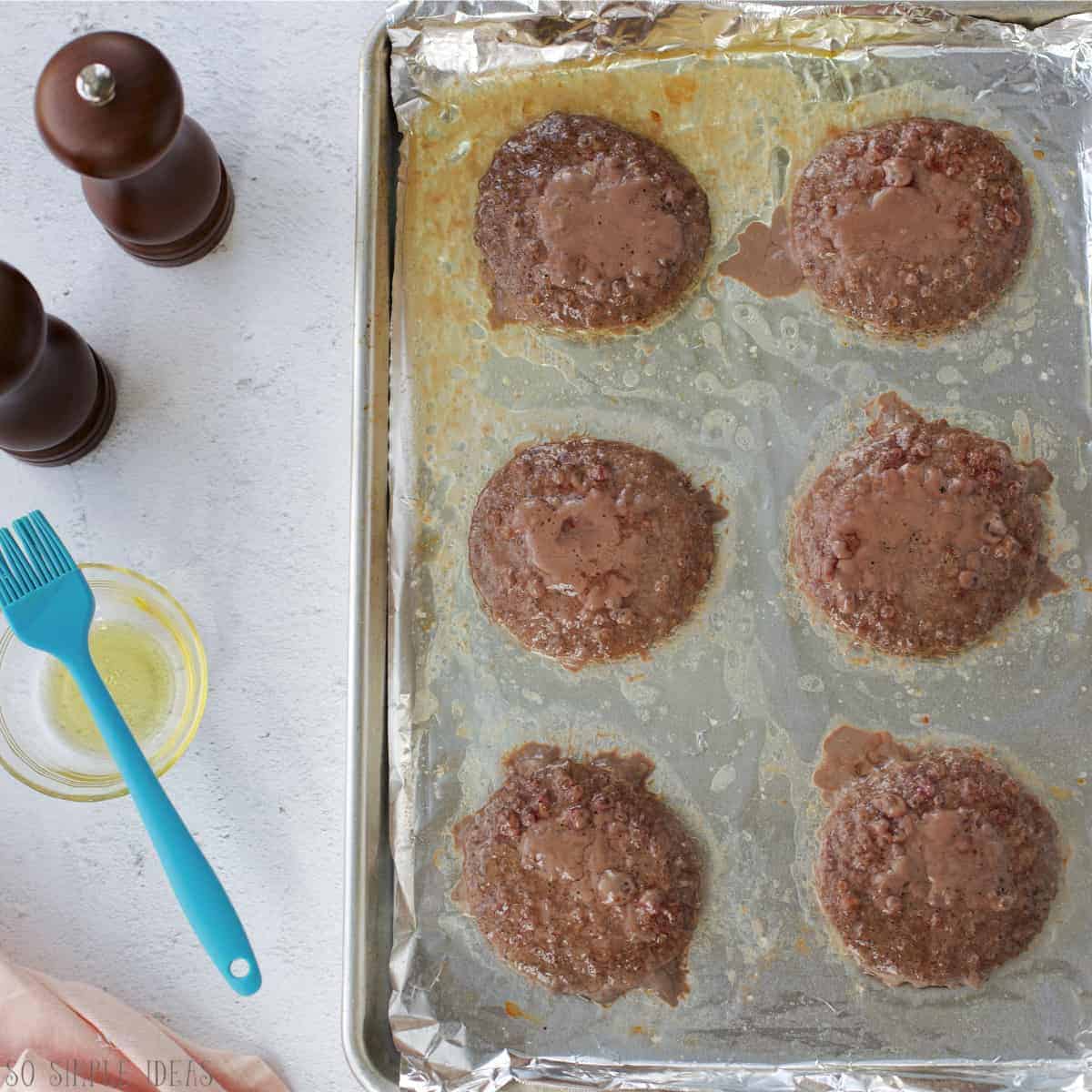 baked hamburger patties on foil lined baking pan.