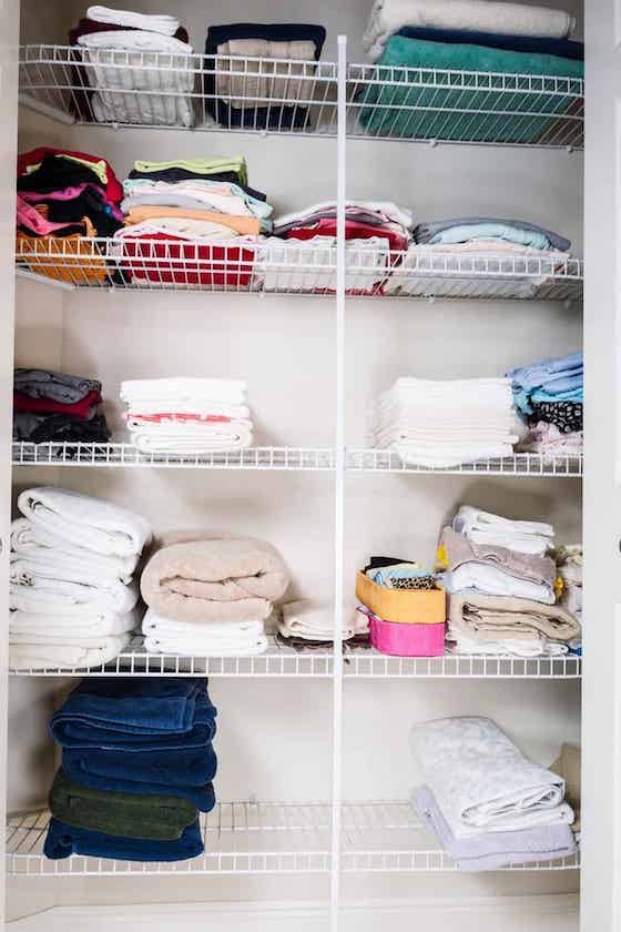 bathroom closet with towels folded on shelves.