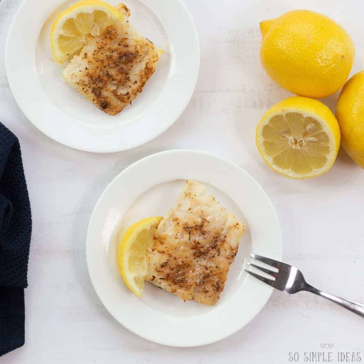 air fryer frozen fish fillets on white plates with lemon.