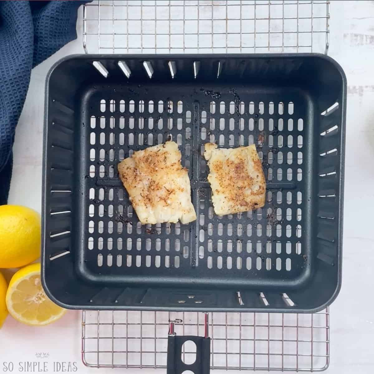 cooked fish fillets in air fryer basket.