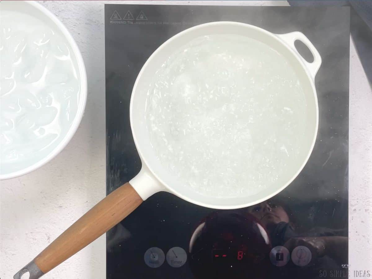 white pot with boiling water and ice bath bowl on side.