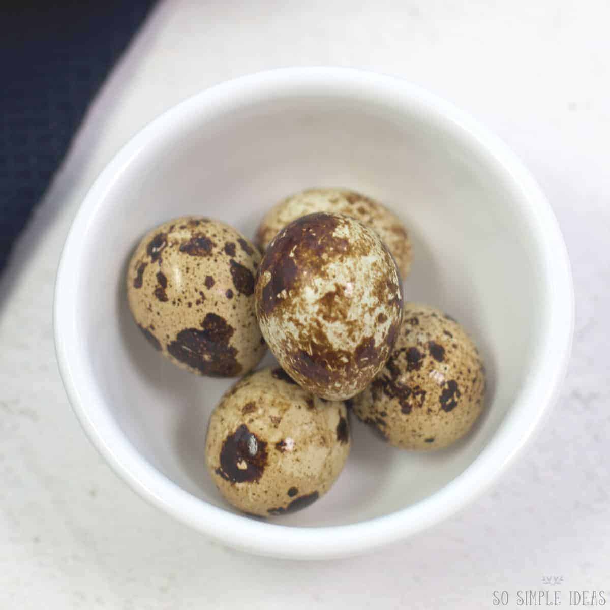 quail eggs in small white bowl.