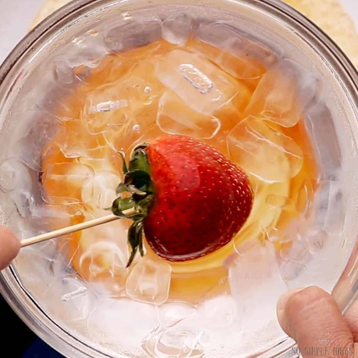 dipping candied strawberry in ice bowl.