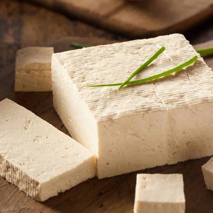 block of tofu sliced on cutting board.