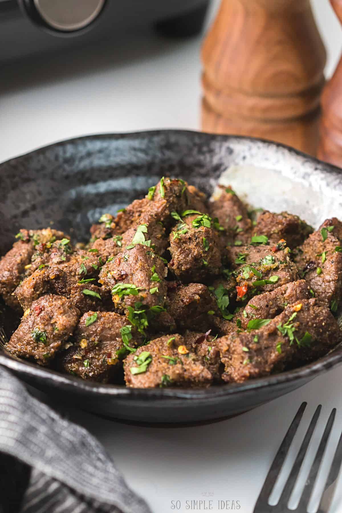 air fryer steak tips in black bowl.