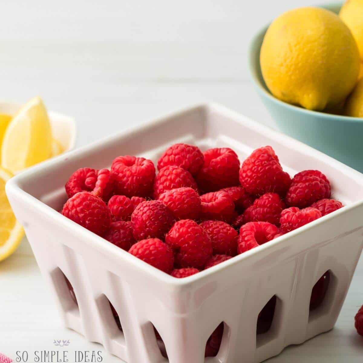 basket of fresh raspberries and bowl of lemons.