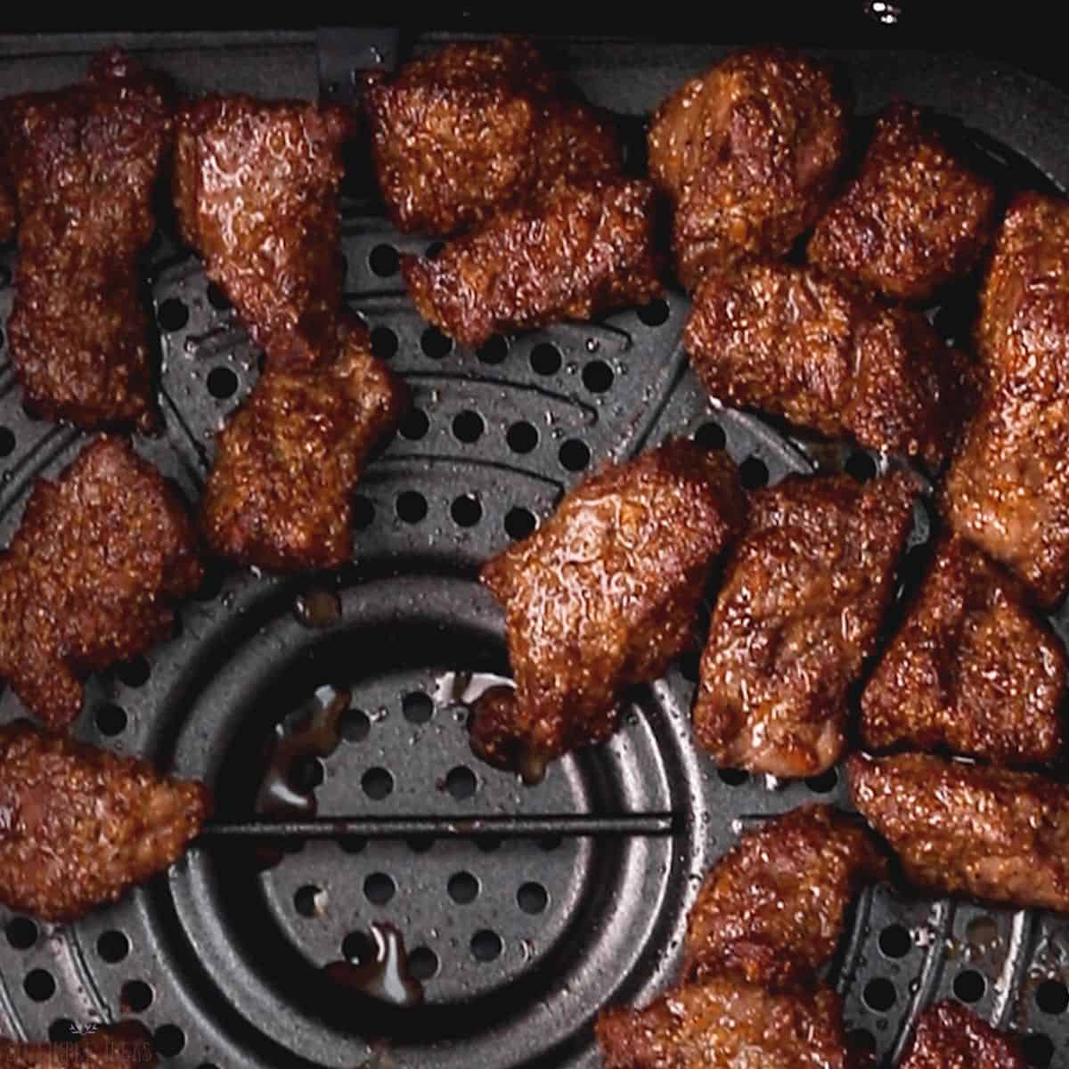 cooked steak tips in air fryer basket.