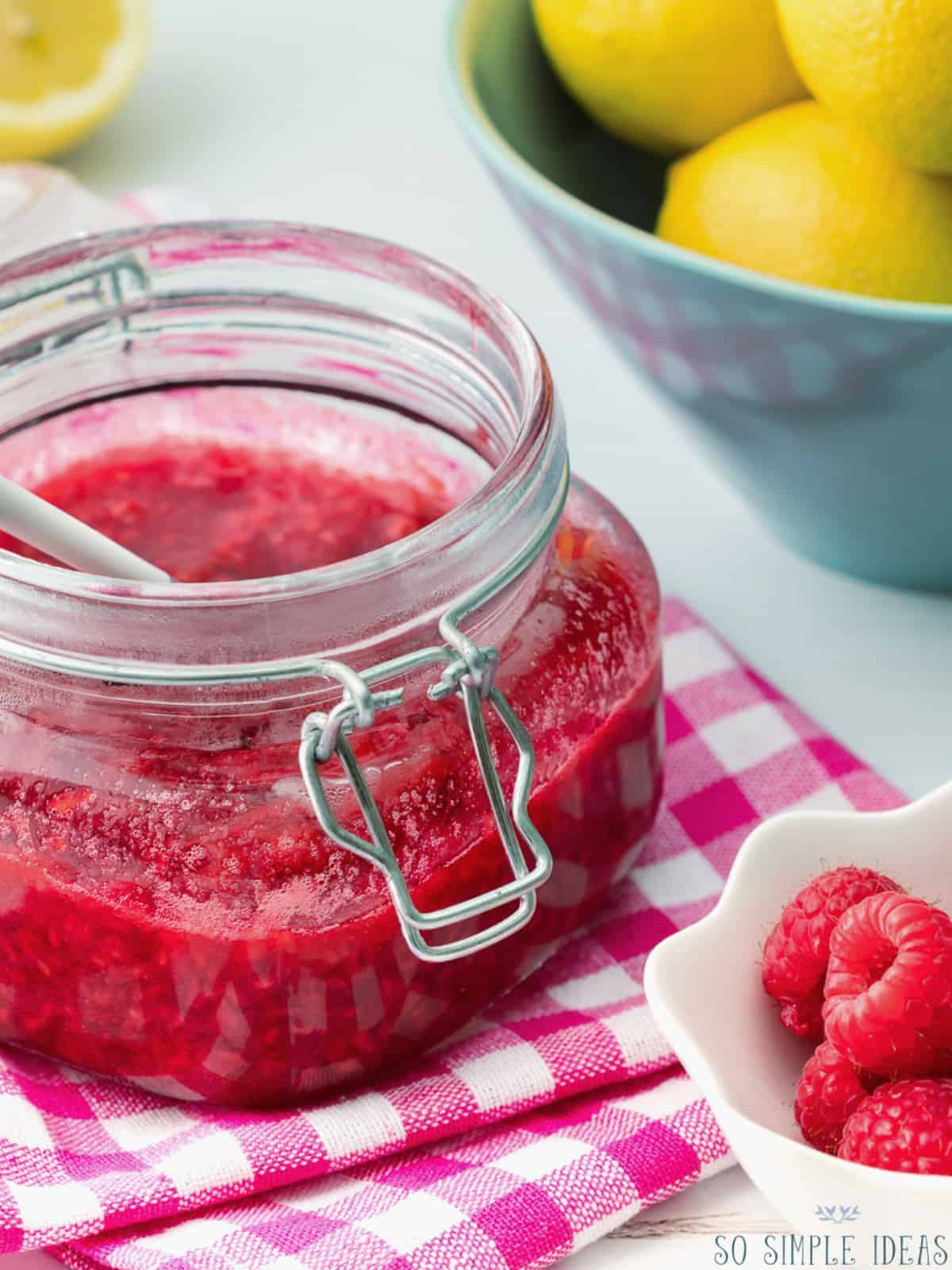 jar of raspberry compote with lemons and berries.