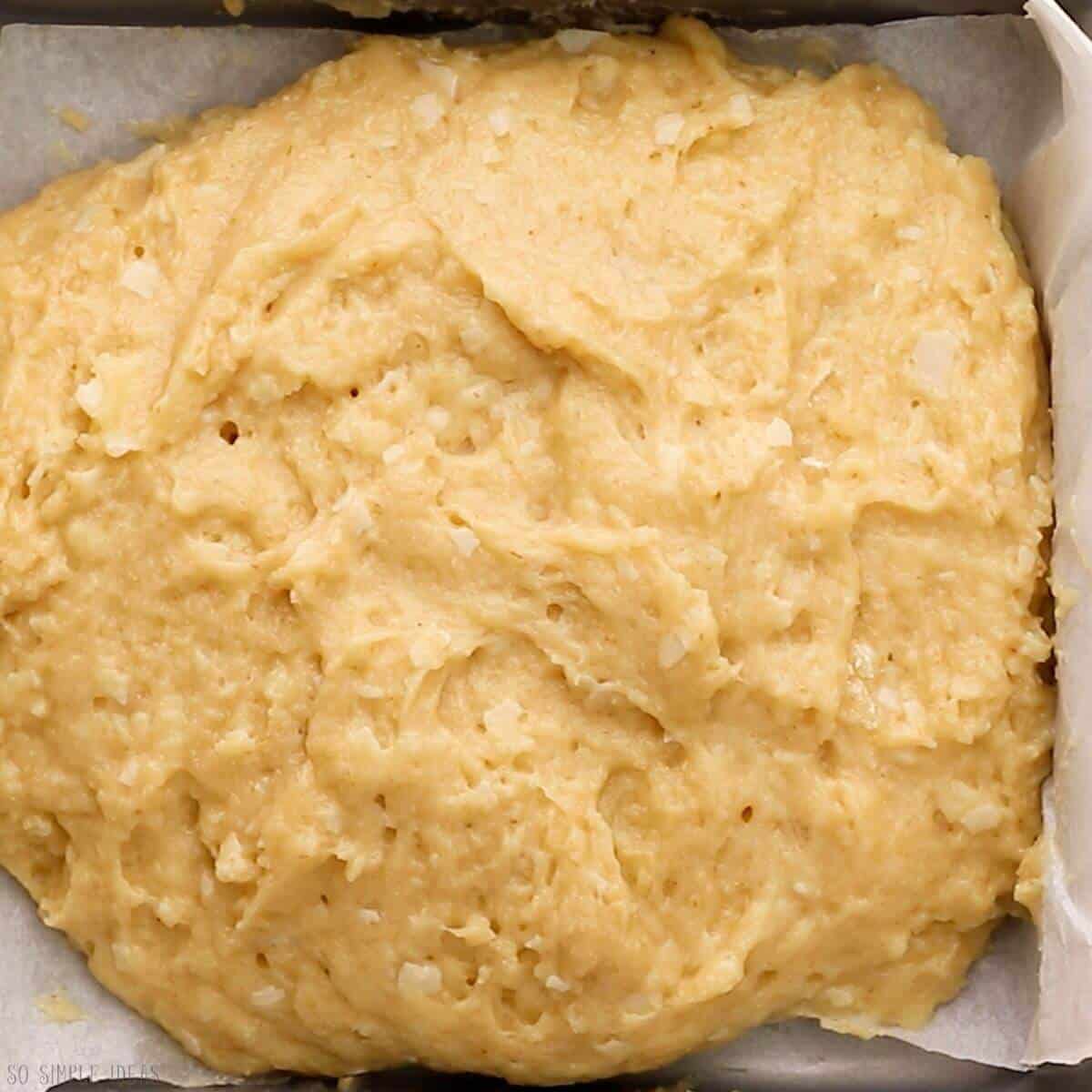 risen bread dough in parchment paper lined baking pan.