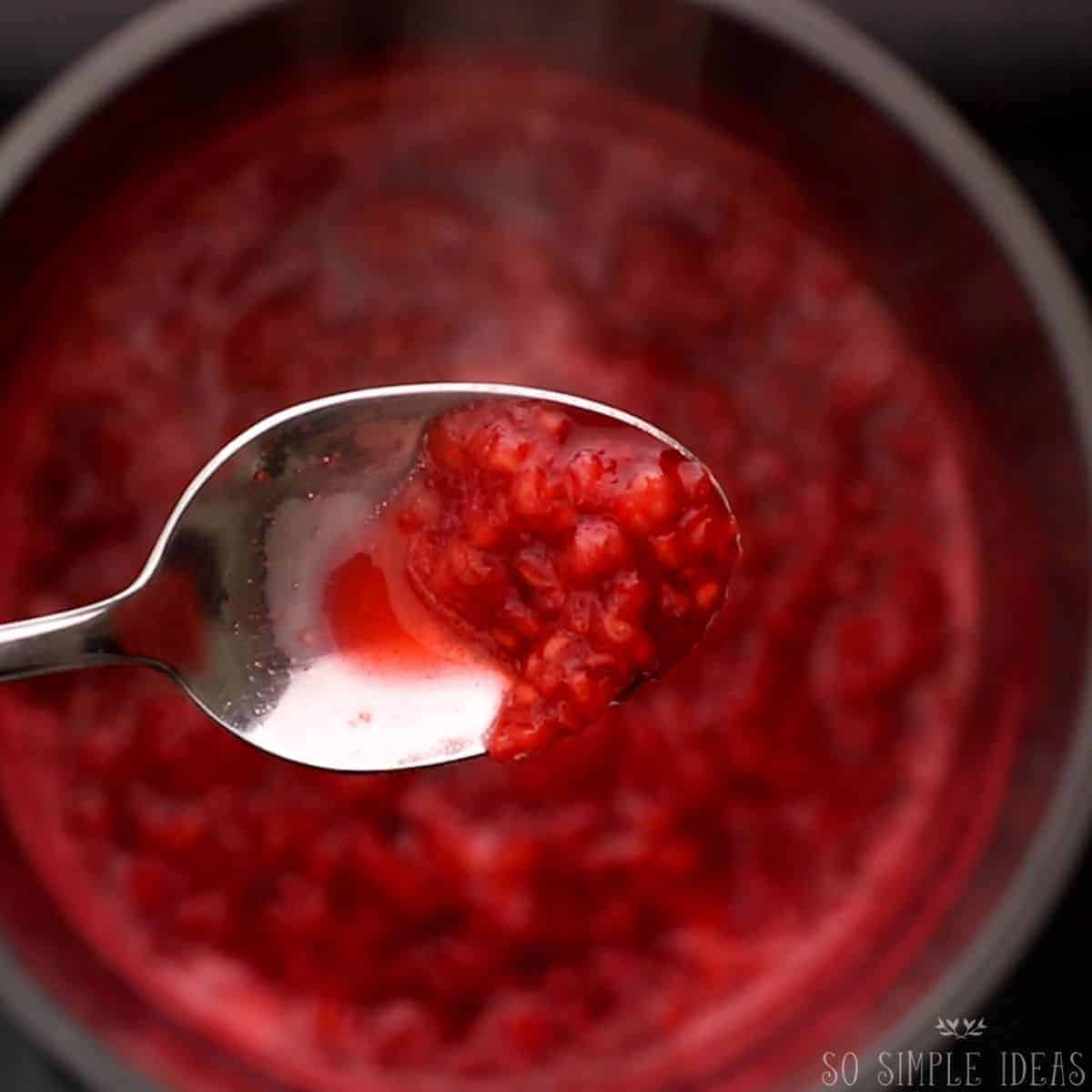 thickened compote on spoon over saucepan.