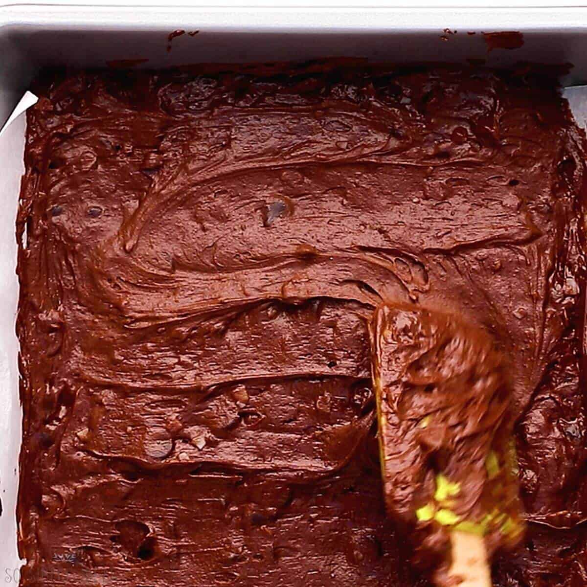 spreading brownie batter into square baking pan.