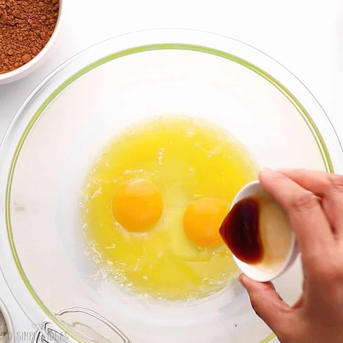 adding vanilla to butter and eggs in glass mixing bowl.