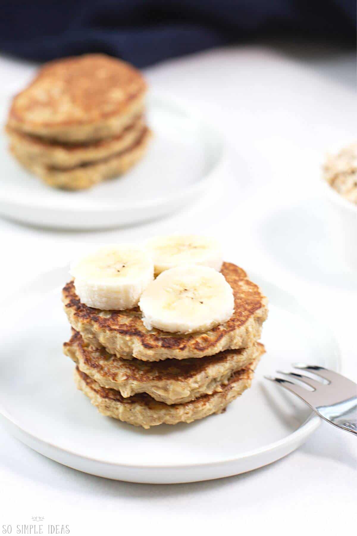 banana oat pancakes stack topped with banana slices.